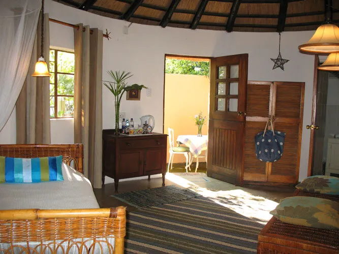 Rondavel interior — thatched ceiling, wooden furniture, and private entrance